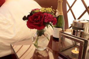 flowers candles and fizz beside yurt bed