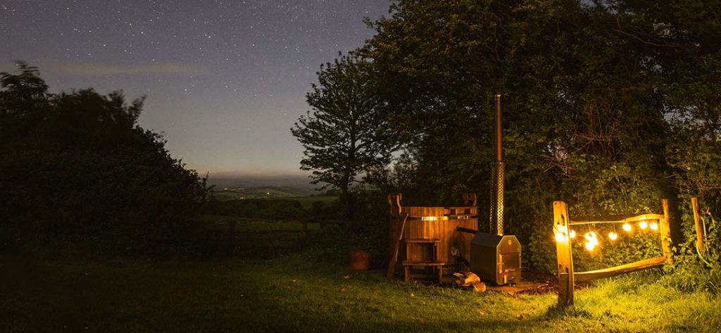 Wood-fired hot tub under the night sky lit by stars